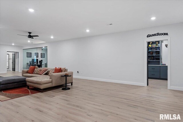 living room featuring a ceiling fan, baseboards, recessed lighting, and light wood-style flooring