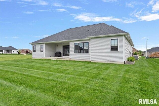 rear view of property with a patio, a ceiling fan, central AC, and a yard