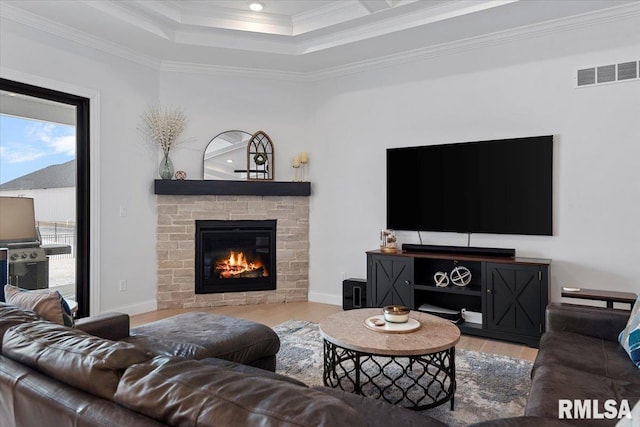 living room featuring a stone fireplace, visible vents, ornamental molding, and wood finished floors