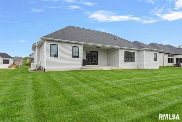 rear view of house featuring a lawn and a ceiling fan