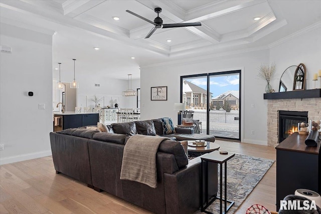living area featuring ornamental molding, beam ceiling, light wood-style floors, a ceiling fan, and coffered ceiling