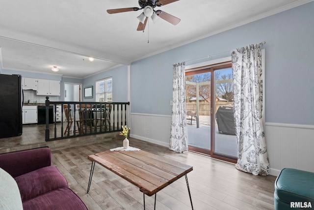 living area with a wainscoted wall, light wood finished floors, and plenty of natural light