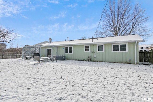 snow covered rear of property featuring a fire pit and fence