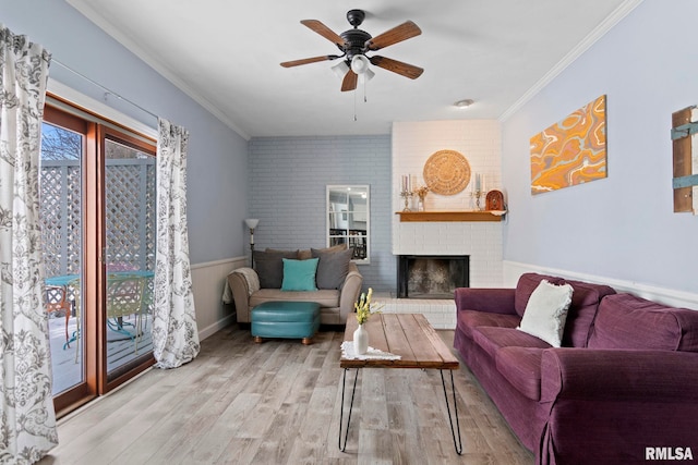 living room featuring crown molding, a ceiling fan, a brick fireplace, and wood finished floors