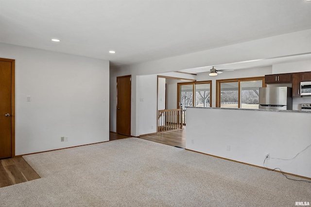 unfurnished living room featuring baseboards, light colored carpet, ceiling fan, light wood-style floors, and recessed lighting