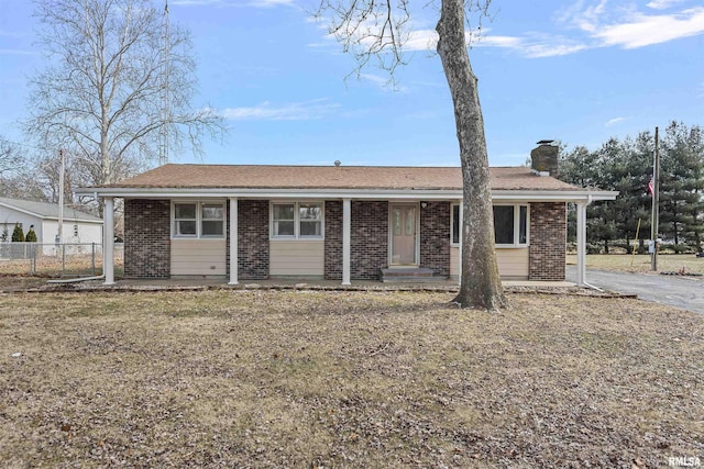 ranch-style home with a front yard, brick siding, fence, and a chimney