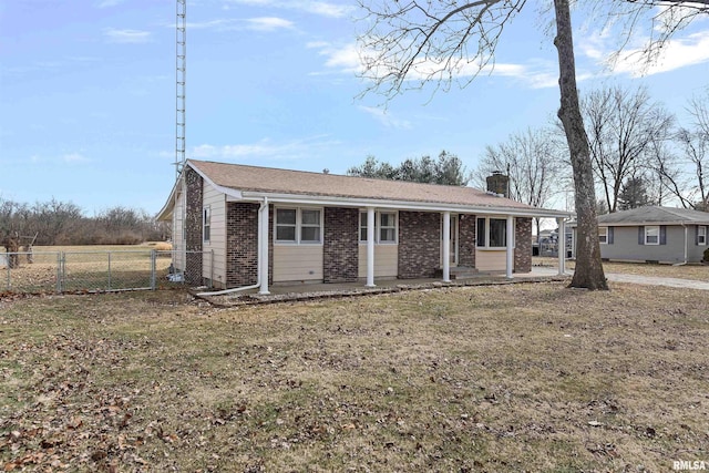 view of front of property with brick siding, a chimney, a front lawn, and fence