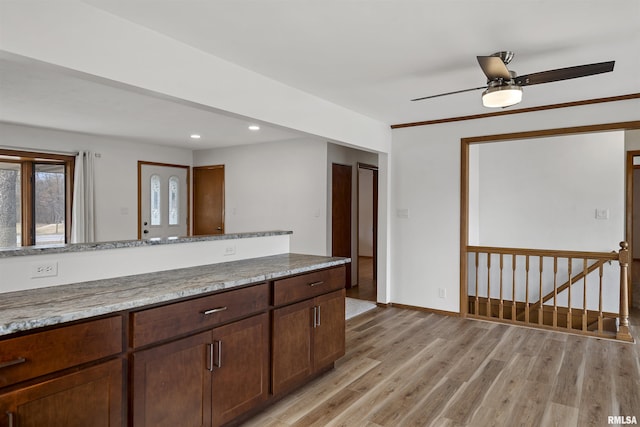 kitchen with light stone counters, recessed lighting, light wood-style floors, dark brown cabinetry, and baseboards