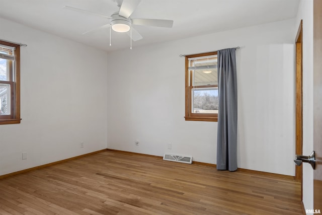 spare room with a ceiling fan, light wood-type flooring, a healthy amount of sunlight, and visible vents