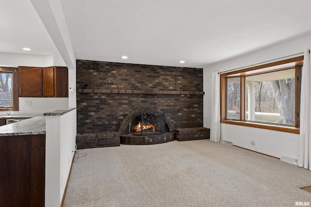 unfurnished living room featuring light carpet, a fireplace, visible vents, and recessed lighting