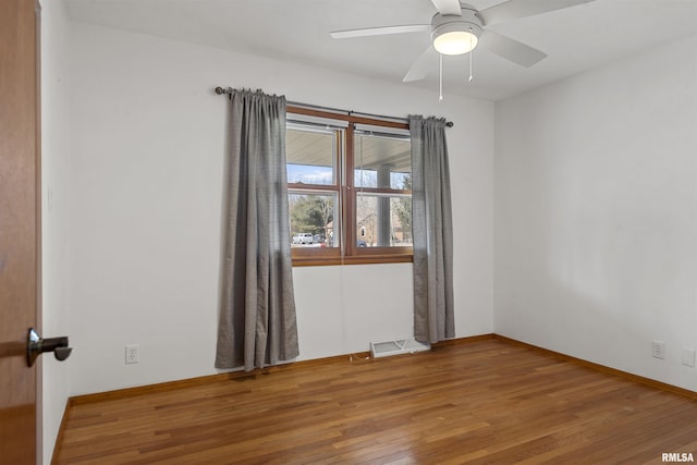 spare room featuring visible vents, ceiling fan, baseboards, and wood finished floors