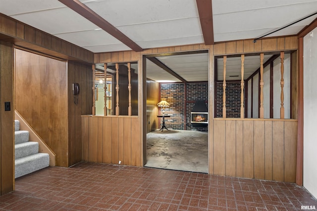 interior space featuring wood walls, stairway, brick floor, and beam ceiling