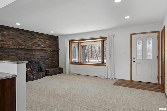 unfurnished living room with light carpet, a fireplace, visible vents, and recessed lighting