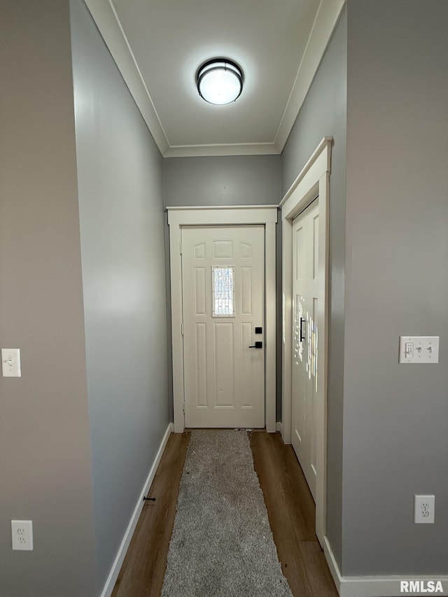 doorway featuring dark wood-style floors, baseboards, and crown molding