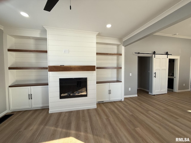 unfurnished living room with ornamental molding, a ceiling fan, a barn door, and baseboards