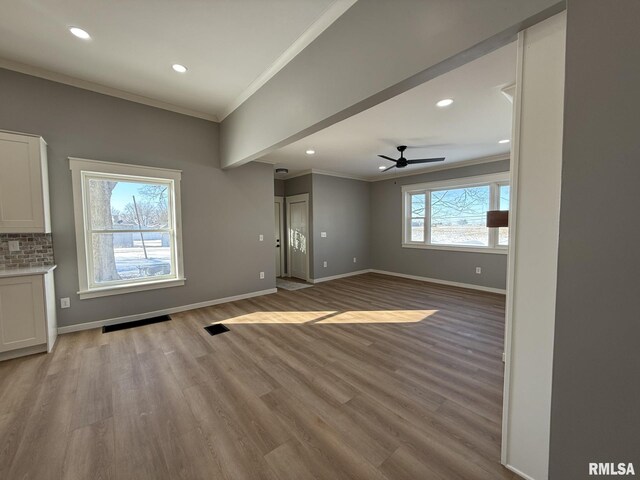 unfurnished living room with a large fireplace, a barn door, ornamental molding, and wood finished floors