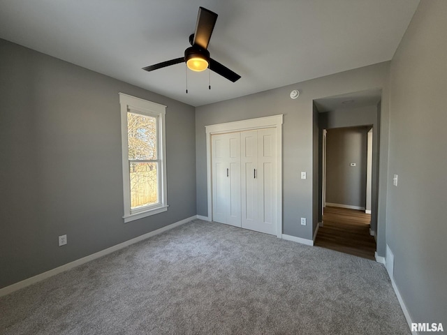 unfurnished bedroom with a closet, ceiling fan, carpet floors, and baseboards