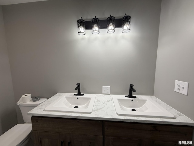 bathroom with double vanity, toilet, and a sink