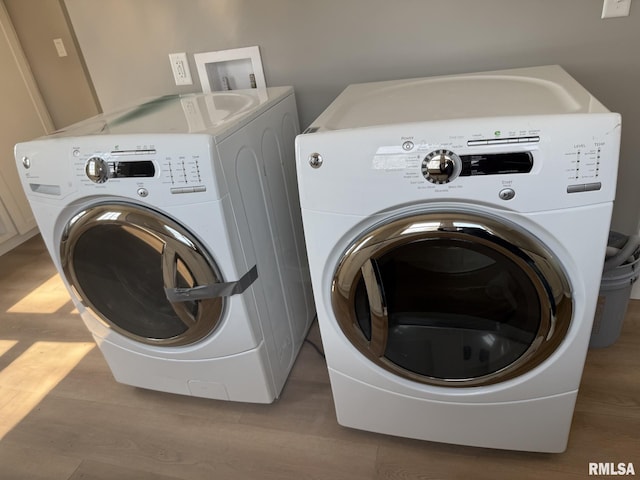 clothes washing area featuring washer and dryer, wood finished floors, and laundry area