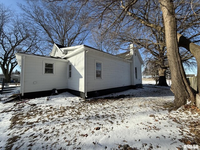 snow covered structure featuring an outbuilding and fence