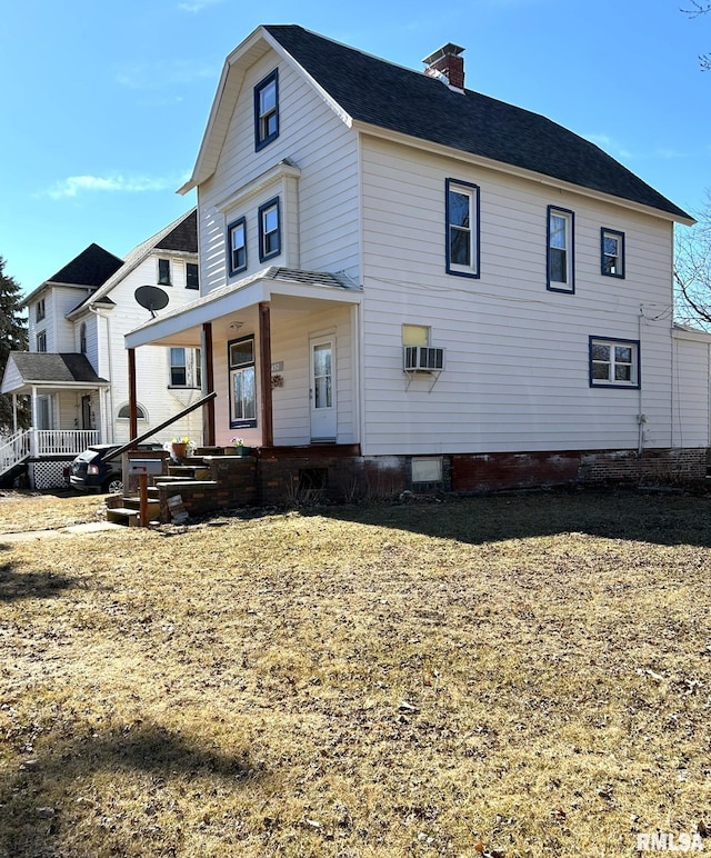 view of front of property featuring covered porch, an AC wall unit, and a chimney