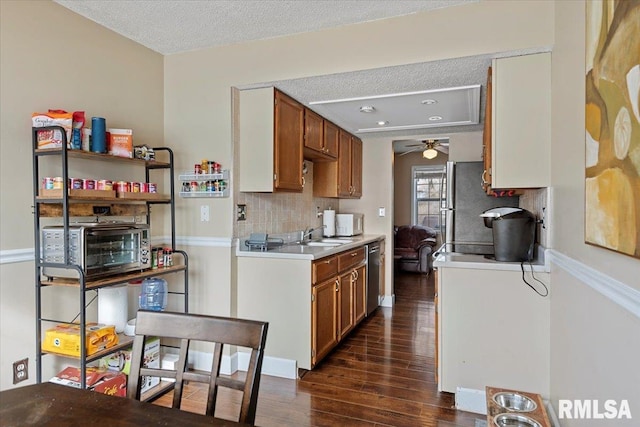 kitchen featuring stainless steel appliances, light countertops, brown cabinets, decorative backsplash, and dark wood finished floors