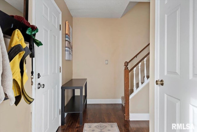 foyer entrance featuring baseboards, a textured ceiling, stairway, and dark wood-type flooring