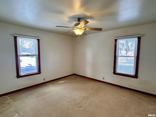 unfurnished room featuring light colored carpet, ceiling fan, and baseboards