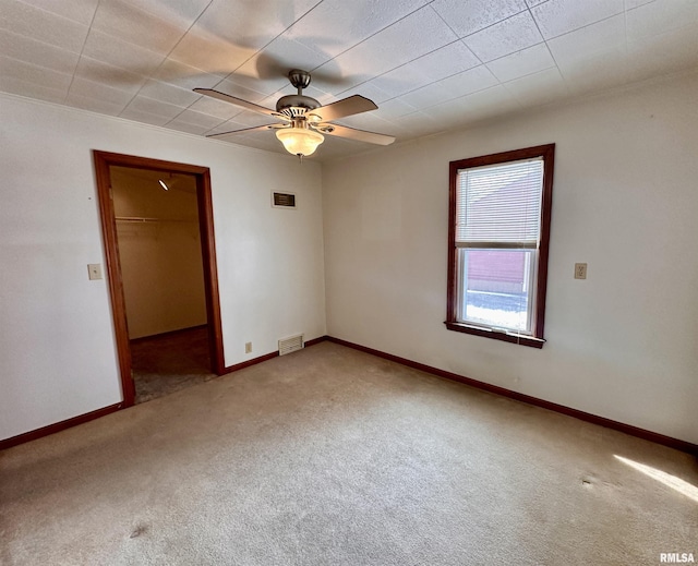 carpeted spare room featuring ceiling fan, visible vents, and baseboards