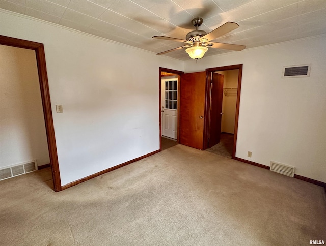 spare room with ceiling fan, visible vents, and light colored carpet