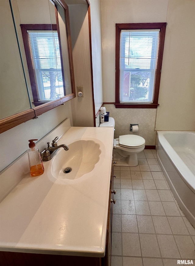 bathroom featuring baseboards, toilet, tile patterned floors, a washtub, and vanity