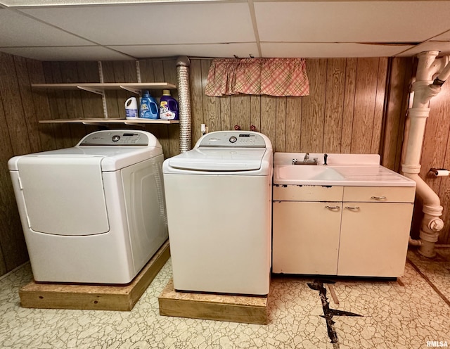 laundry room featuring cabinet space, wooden walls, and separate washer and dryer