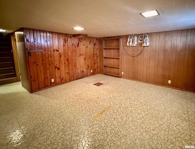 finished basement with wood walls, baseboards, and stairs