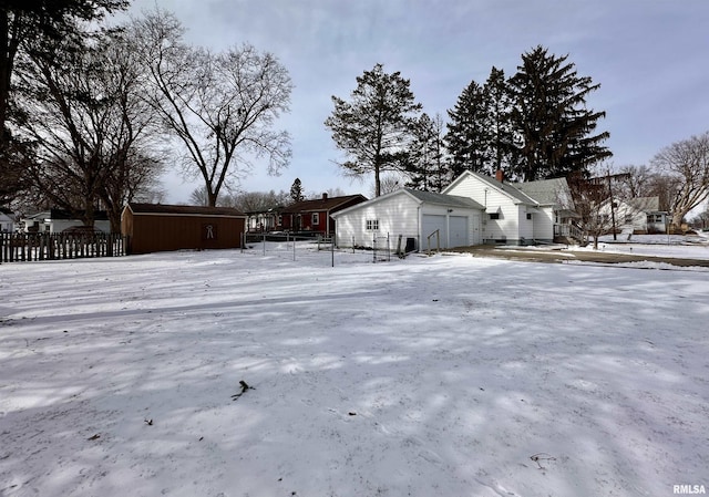 snowy yard featuring a garage, a residential view, and fence