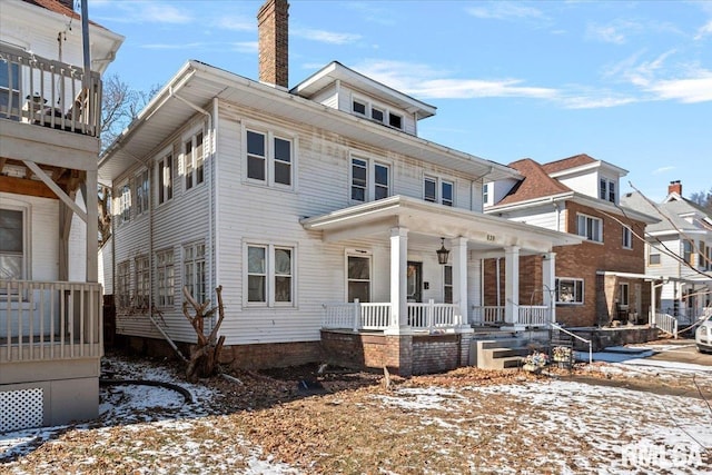 american foursquare style home featuring a porch and a chimney