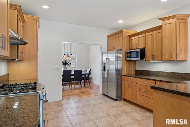 kitchen with light tile patterned floors, recessed lighting, under cabinet range hood, appliances with stainless steel finishes, and dark stone countertops