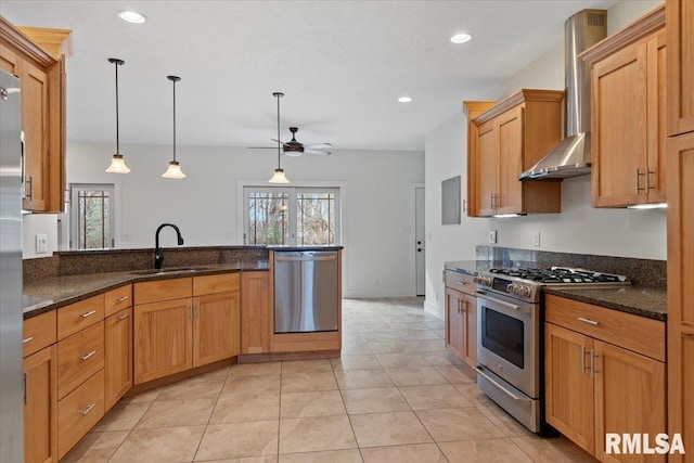 kitchen featuring plenty of natural light, hanging light fixtures, stainless steel appliances, wall chimney range hood, and a sink