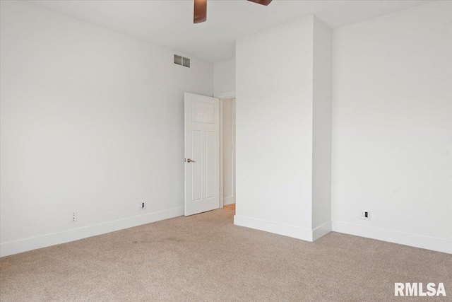 spare room featuring light colored carpet, visible vents, ceiling fan, and baseboards