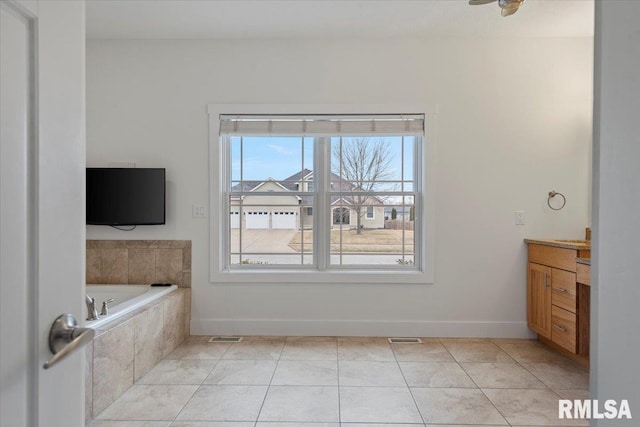 bathroom featuring tiled bath, visible vents, baseboards, tile patterned floors, and vanity