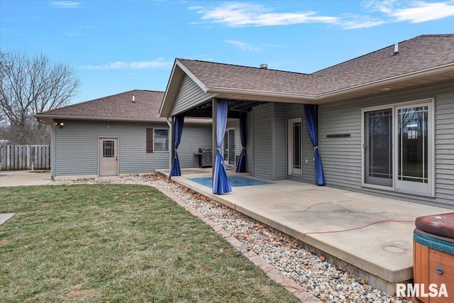 back of house with roof with shingles, a patio, a lawn, and fence