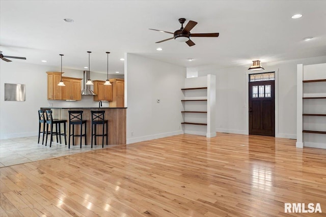 unfurnished living room featuring baseboards, light wood-type flooring, a ceiling fan, and recessed lighting