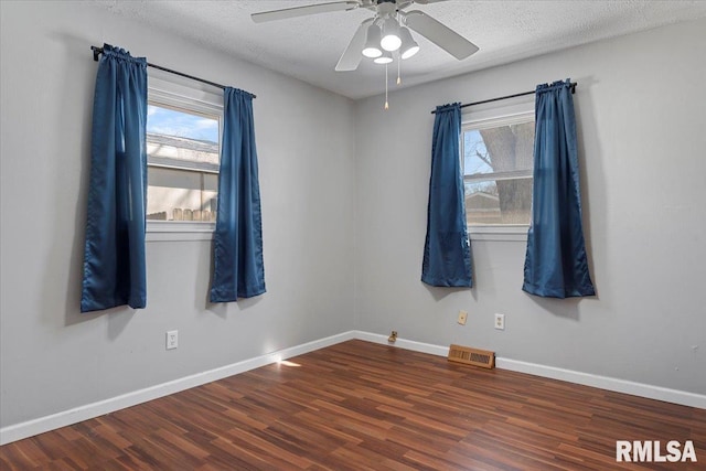 unfurnished room with baseboards, visible vents, and dark wood-style flooring