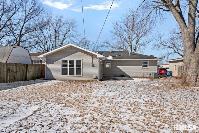 snow covered property featuring central AC and fence