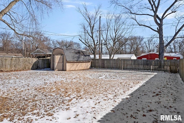 yard covered in snow featuring an outbuilding, a fenced backyard, and a shed