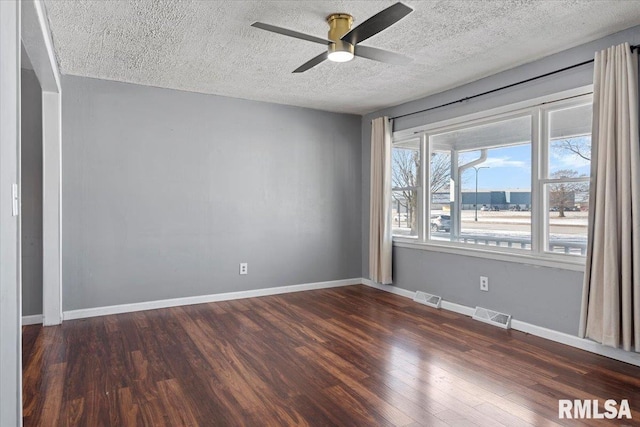 spare room with baseboards, visible vents, and dark wood finished floors