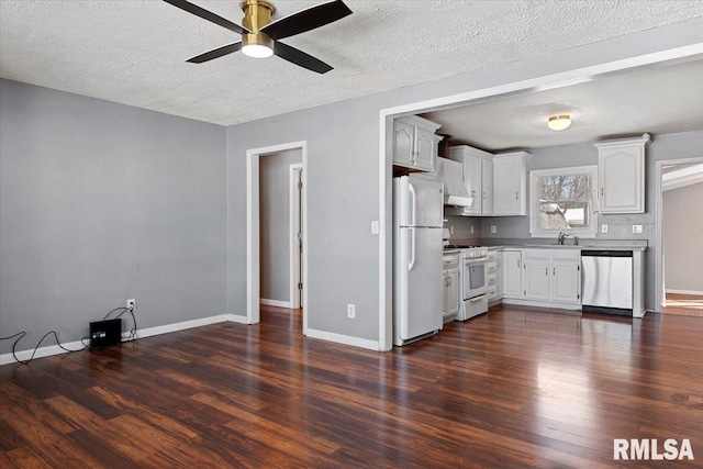 kitchen with dark wood finished floors, white appliances, a sink, and white cabinetry