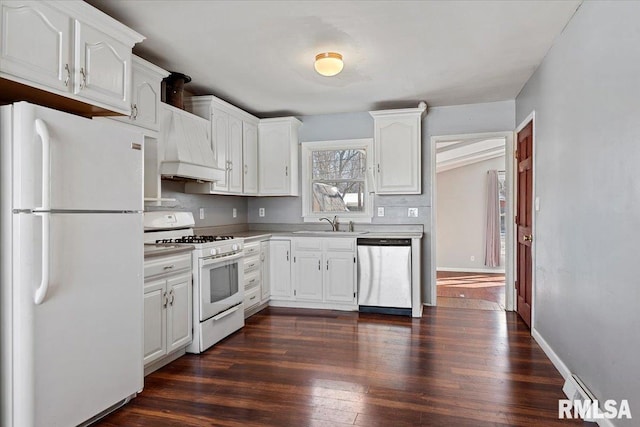 kitchen featuring white appliances, dark wood-style flooring, a sink, white cabinetry, and custom range hood