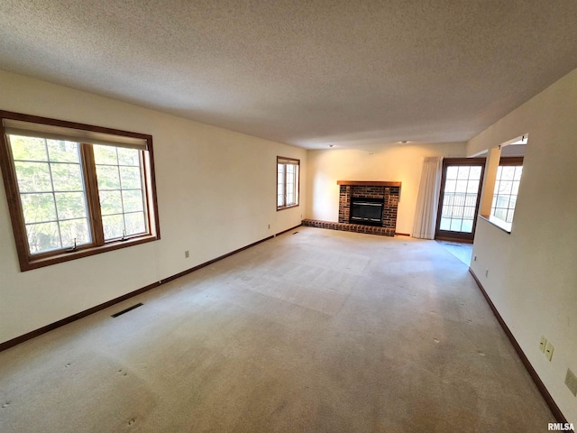 unfurnished living room with a brick fireplace, baseboards, visible vents, and light colored carpet