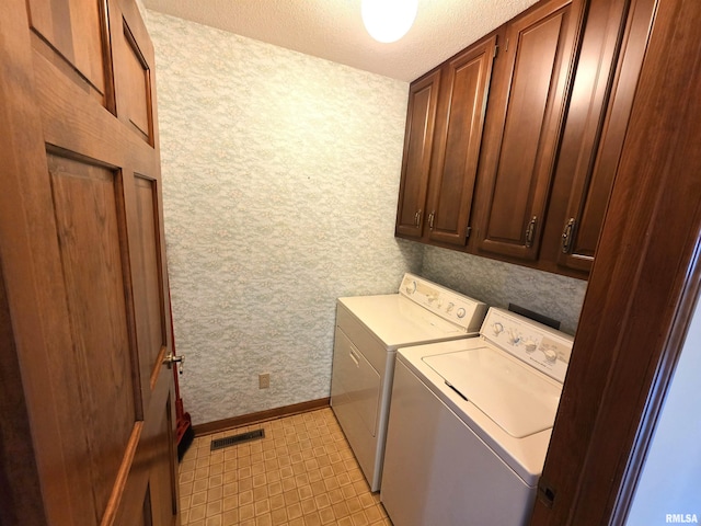 washroom featuring cabinet space, baseboards, visible vents, a textured ceiling, and separate washer and dryer