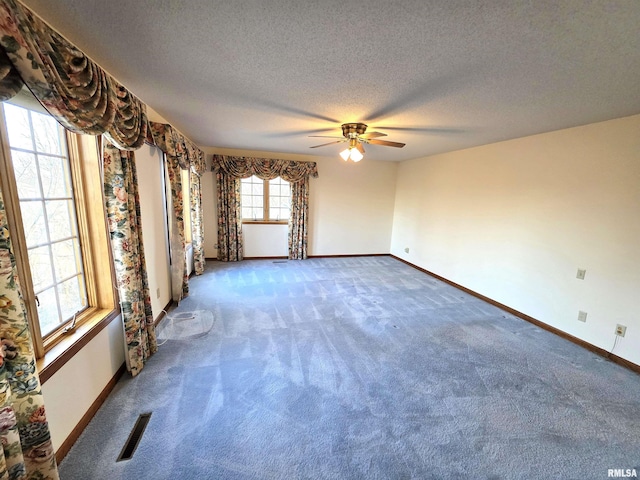 spare room featuring carpet flooring, visible vents, a textured ceiling, and baseboards